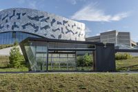 a large glass building with geometric designs on it's side and a long driveway leading to it