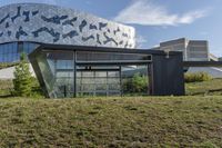 a large glass building with geometric designs on it's side and a long driveway leading to it