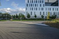 a city street surrounded by grass and tall buildings at the end of a street there is a paved pathway in front of the building