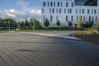 a city street surrounded by grass and tall buildings at the end of a street there is a paved pathway in front of the building