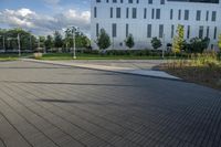 a city street surrounded by grass and tall buildings at the end of a street there is a paved pathway in front of the building