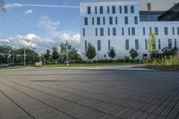 a city street surrounded by grass and tall buildings at the end of a street there is a paved pathway in front of the building