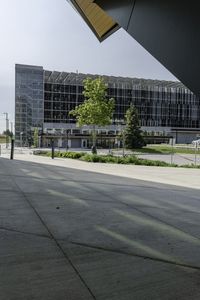 a man on his skateboard next to an airport terminal building with some trees and bushes