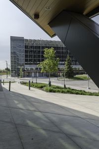 a man on his skateboard next to an airport terminal building with some trees and bushes