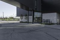 a black building with concrete pillars on both sides and green lawn in front of the entrance