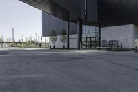 a black building with concrete pillars on both sides and green lawn in front of the entrance