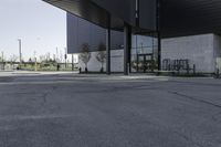 a black building with concrete pillars on both sides and green lawn in front of the entrance