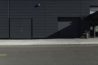 a black building with a sign on the front door and doors closed next to the road