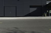 a black building with a sign on the front door and doors closed next to the road