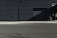 a black building with a sign on the front door and doors closed next to the road