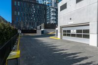 a parking garage is next to an industrial warehouse building with large windows in it, on the side of a city street