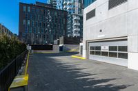 a parking garage is next to an industrial warehouse building with large windows in it, on the side of a city street