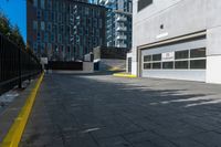 a parking garage is next to an industrial warehouse building with large windows in it, on the side of a city street