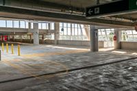 a empty parking garage in an industrial building with large windows and doors on each floor