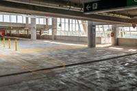 a empty parking garage in an industrial building with large windows and doors on each floor