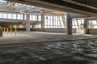 a empty parking garage in an industrial building with large windows and doors on each floor