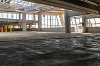 a empty parking garage in an industrial building with large windows and doors on each floor