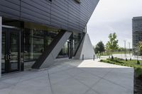 a sidewalk next to a modern building in a city area with concrete walls and cemented pavement