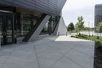 a sidewalk next to a modern building in a city area with concrete walls and cemented pavement