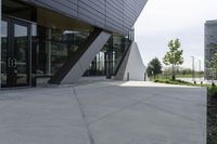 a sidewalk next to a modern building in a city area with concrete walls and cemented pavement