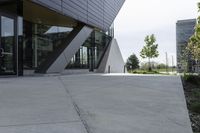 a sidewalk next to a modern building in a city area with concrete walls and cemented pavement