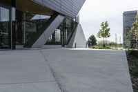 a sidewalk next to a modern building in a city area with concrete walls and cemented pavement