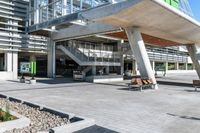 there are benches in the outdoor area of a large building that's under a walkway