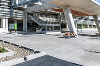 there are benches in the outdoor area of a large building that's under a walkway