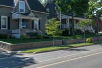 a man skateboarding along a residential street in a city, and there is also a brick wall on the side