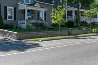 a man skateboarding along a residential street in a city, and there is also a brick wall on the side