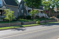 a man skateboarding along a residential street in a city, and there is also a brick wall on the side