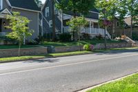 a man skateboarding along a residential street in a city, and there is also a brick wall on the side