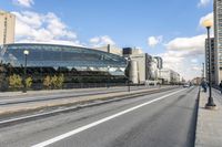 two roads that pass near a bus station on the street outside of a building with large glass structure