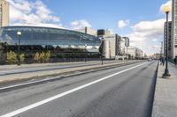 two roads that pass near a bus station on the street outside of a building with large glass structure