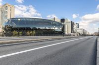 two roads that pass near a bus station on the street outside of a building with large glass structure