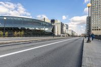 two roads that pass near a bus station on the street outside of a building with large glass structure