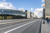 two roads that pass near a bus station on the street outside of a building with large glass structure