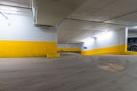 a car sits in an empty parking garage near yellow lines and yellow paint on the floors