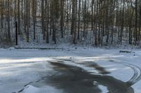 the road has two tires on the snow and a line of trees that is on top of a snowy hill