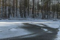 the road has two tires on the snow and a line of trees that is on top of a snowy hill