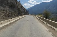 road with mountains in the back ground and cars parked at the side of the road