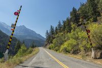 a road with the highway going through it is marked in black with a stop sign and mountains are behind