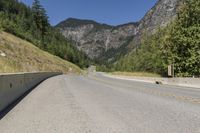 the view down an empty highway in the mountains near the road and sign for the road