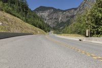 the view down an empty highway in the mountains near the road and sign for the road