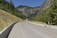 the view down an empty highway in the mountains near the road and sign for the road