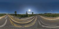 a road and two lanes with multiple yellow painted lines on them under blue skies with a sun