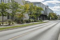 the roadway in front of the building is empty with grass on both sides of the road