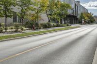 the roadway in front of the building is empty with grass on both sides of the road