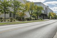 the roadway in front of the building is empty with grass on both sides of the road