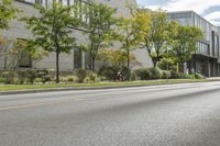 the roadway in front of the building is empty with grass on both sides of the road